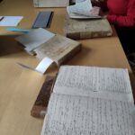 Photographie en couleurs de gros registres d'archives posés sur une table